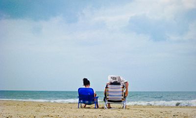 Two people sitting on beach in chairs